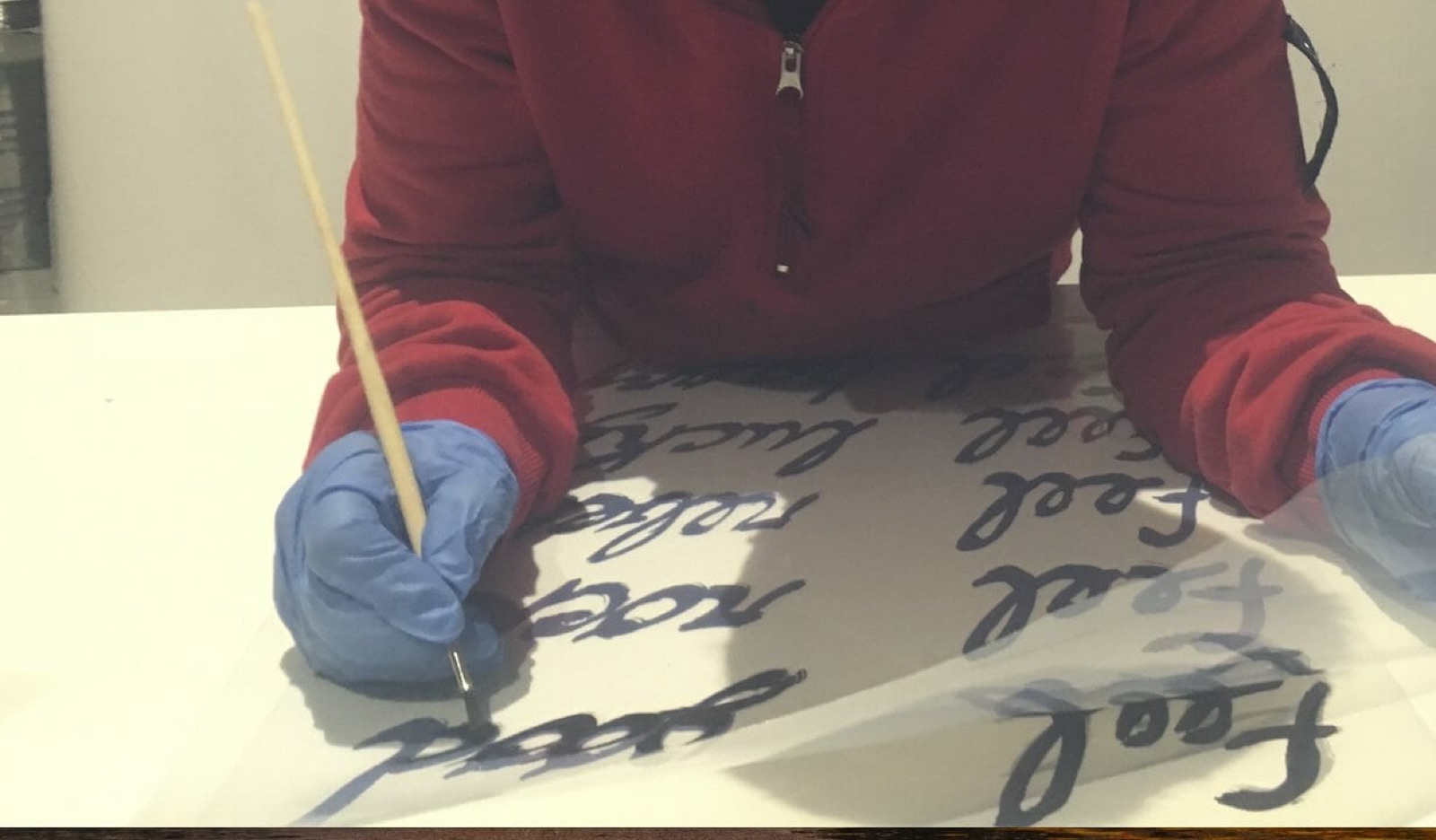 Mani con i guanti che tracciano un lettering su pellicola
