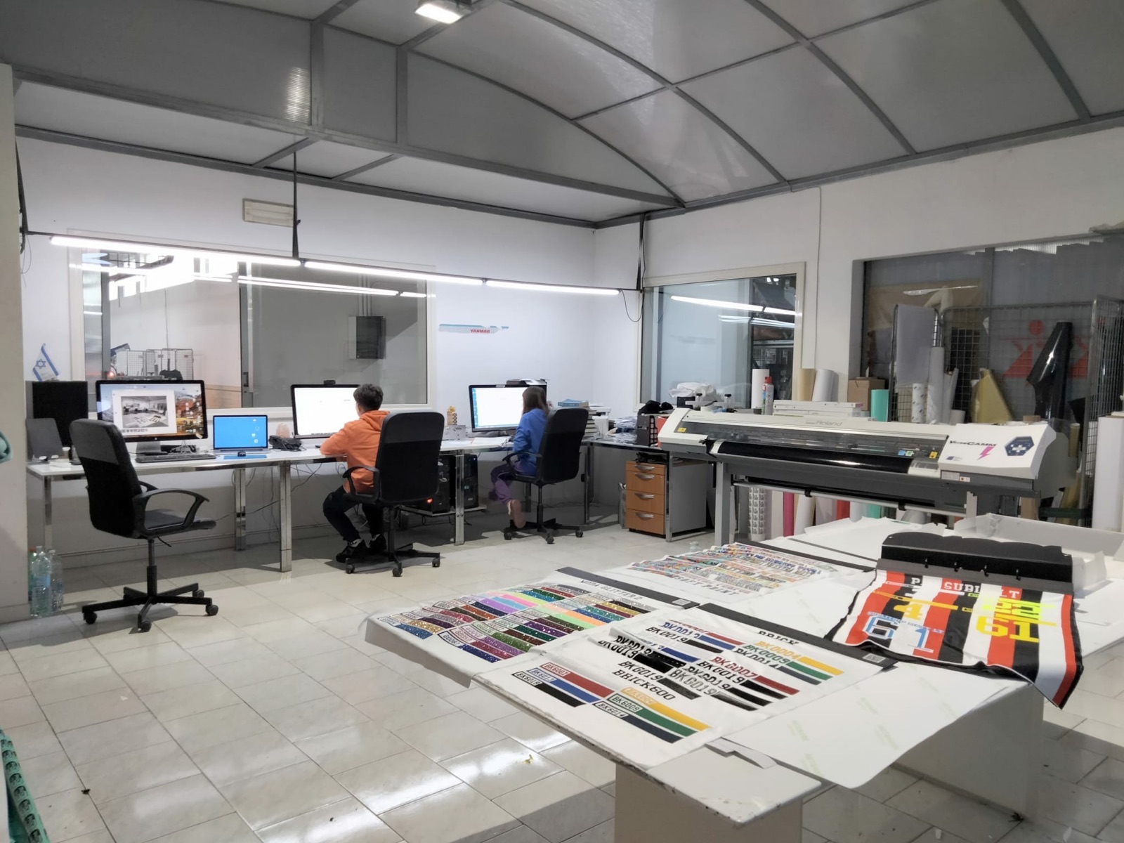 Ufficio grafico con postazioni di lavoro e campioni di stampa