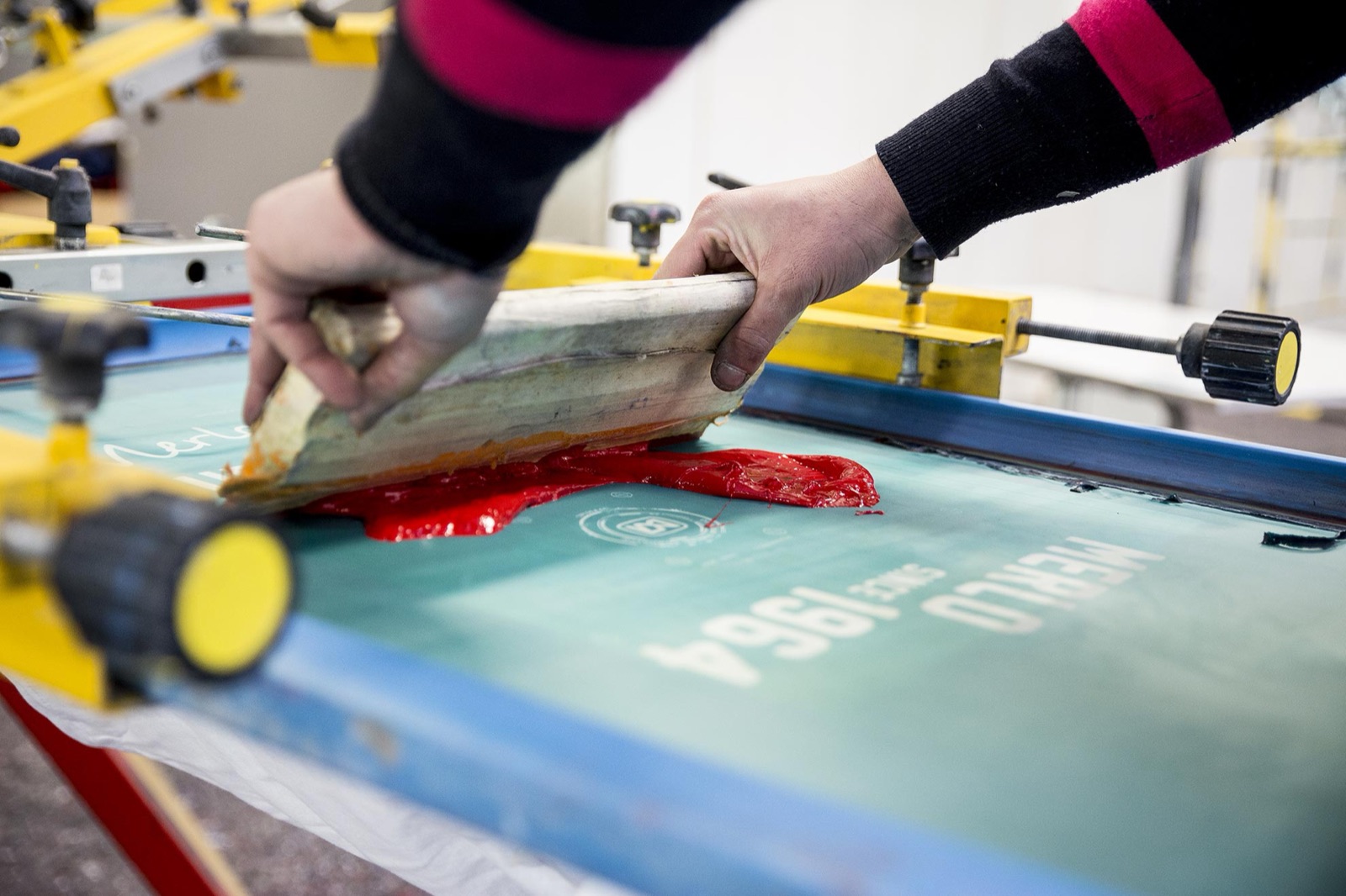 Stampatore che passa la racla su un telaio serigrafico
